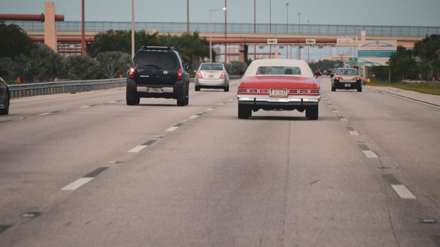 Illustrative image: Highway traffic scene with classic car in Miami, Florida, showcasing urban travel atmosphere.
