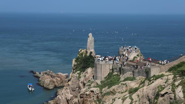 View of visitors at Changdao National Nature Reserve with sea and rocks.