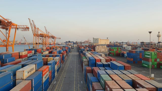 Illustrative image: A bustling port scene with colorful cargo containers at sunrise. Ideal for logistics concepts.