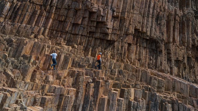 Adventurers scaling unique volcanic rock formations outdoors.