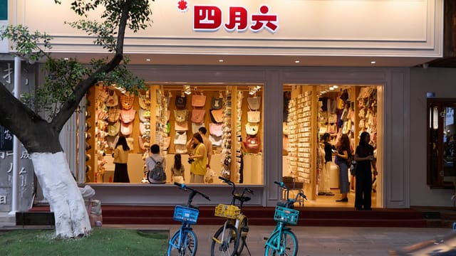 Charming boutique with colorful bags and people browsing, bicycles parked outside at dusk.
