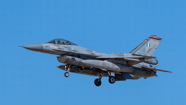 F-16 fighter jet flying against a clear blue sky, showcasing military aviation power.