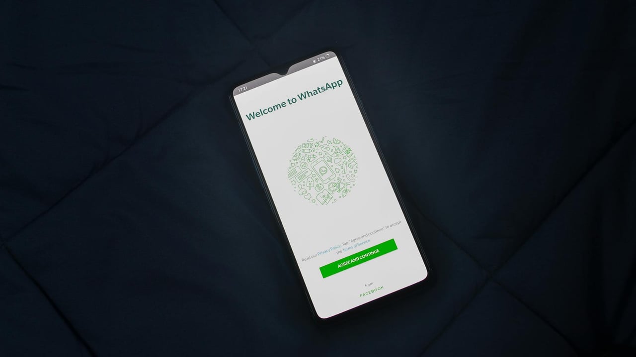 Smartphone displaying WhatsApp login screen on a dark surface. Overhead view.
