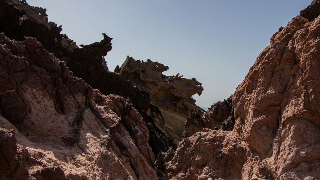 Breathtaking rock formations under clear blue sky on Hormoz Island's arid landscape.