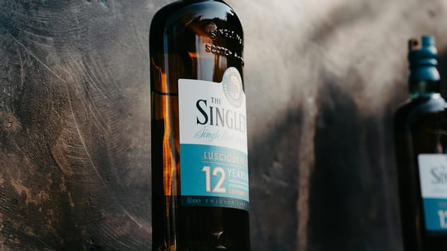 Close-up of a 12-year-old single malt whisky bottle with elegant design on a textured background.