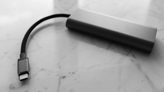 A minimalist black and white image of a USB-C power bank on a marble surface.