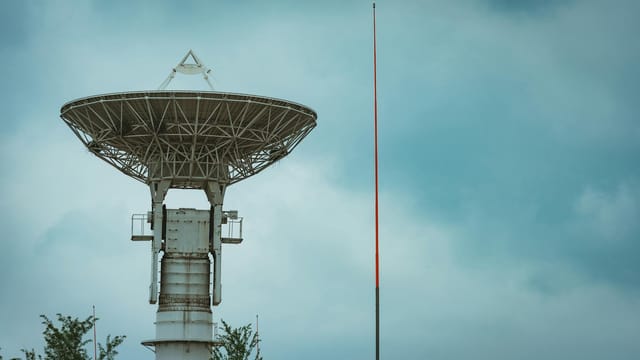 Large satellite dish tower standing tall under a cloudy sky.