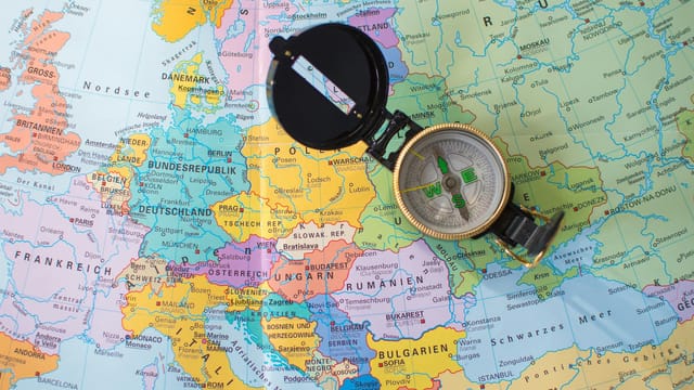 A flat lay image of a compass on a map of Europe, symbolizing travel and direction planning.