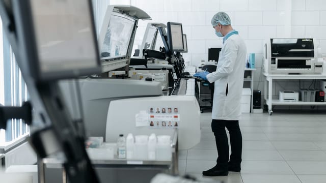 A scientist in a lab coat using advanced laboratory equipment in a clean, modern lab.