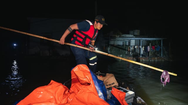 A rescue worker in Phú Yên, Vietnam, aids flood victims during nighttime operations.