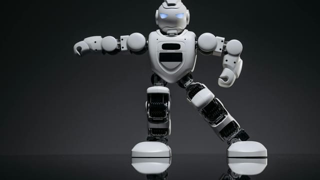 Close-up of a white toy robot with glowing eyes on a reflective black surface.