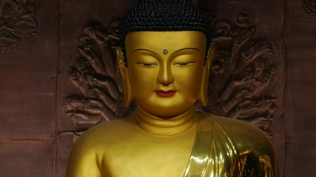 Serene golden Buddha statue against detailed carved backdrop in a Seoul temple.