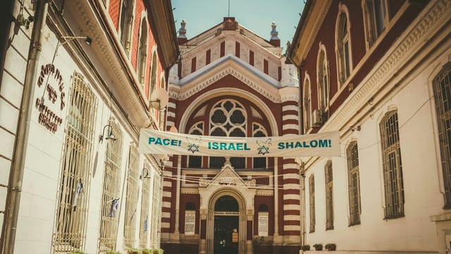 Gothic Revival architecture of Brașov Synagogue with a peace message banner under daylight.
