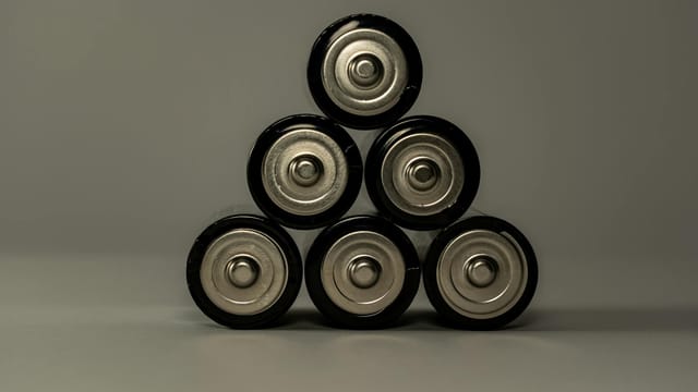 Metallic AA batteries stacked in a pyramid shape, symbolizing power and energy storage.