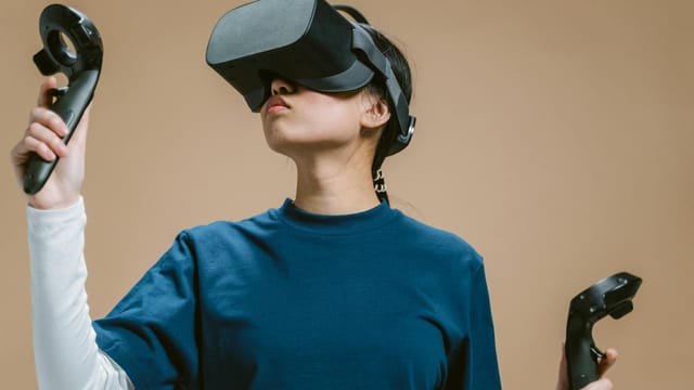 Woman engaging with virtual reality using a VR headset and controllers.