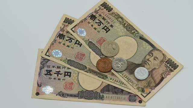 Close-up of Japanese Yen banknotes and coins arranged on a flat surface.