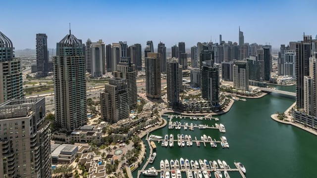 Stunning aerial view of Dubai Marina's skyline and waterfront, showcasing modern architecture and luxury yachts.