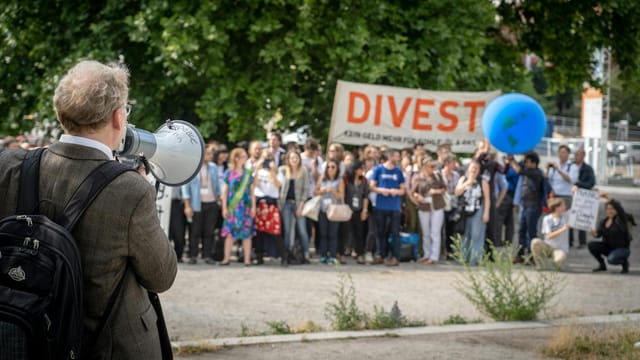Protesters gather in Berlin, Germany, advocating for divestment and environmental action.