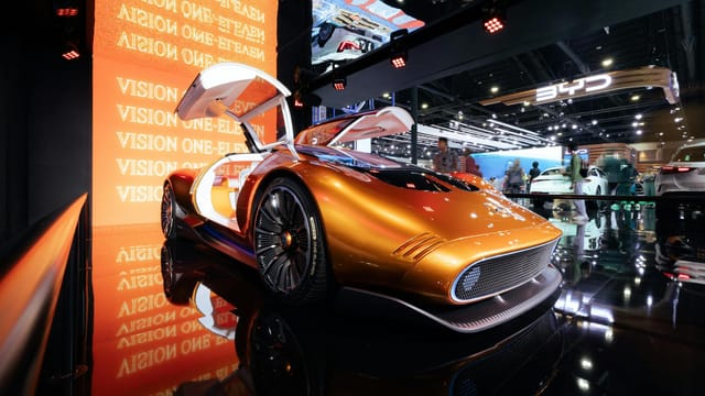 A sleek futuristic concept car in vivid orange displayed at an international motor show.