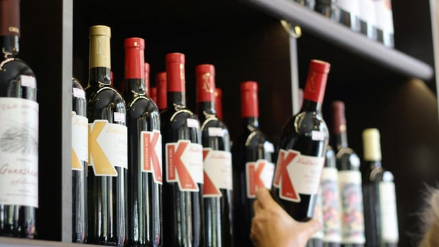 A selection of red wine bottles with bold labels on a store shelf.