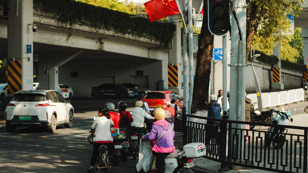 Busy urban street corner with mopeds in China, under overpass.