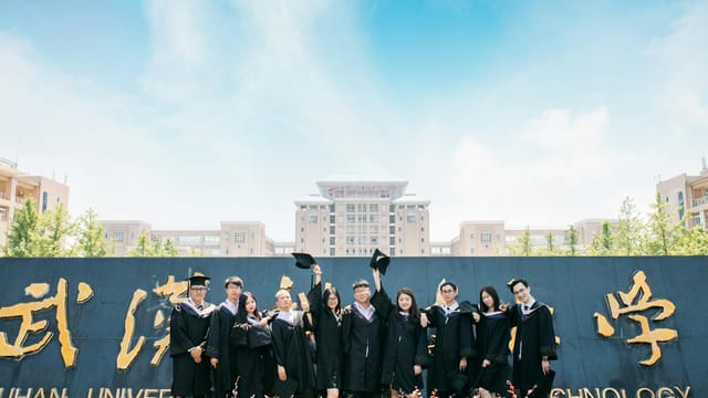 Group of graduates celebrating outdoors at Wuhan University of Technology.