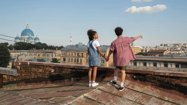 A couple enjoys a rooftop view of Saint Petersburg, holding hands under the sunny sky.