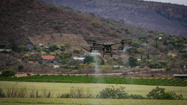 High-tech drone spraying crops for precision agriculture in a rural setting.