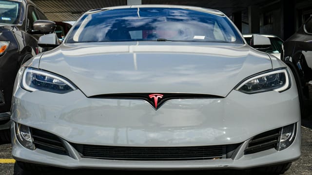 Front view of a Tesla Model S parked in an urban area, highlighting sleek design and modern aesthetics.