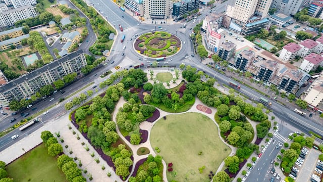 Aerial view showcasing a city park and bustling roundabout in a vibrant urban area.