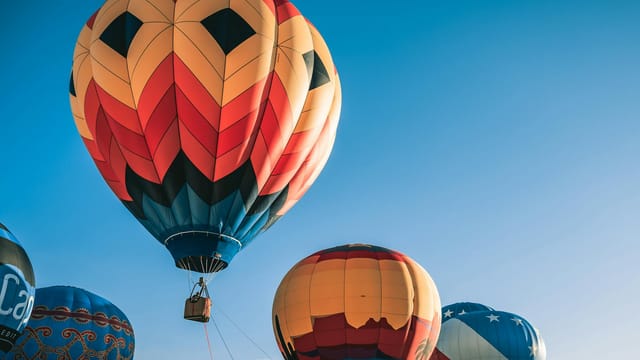 Colorful hot air balloons floating in a clear blue sky, perfect for travel enthusiasts.