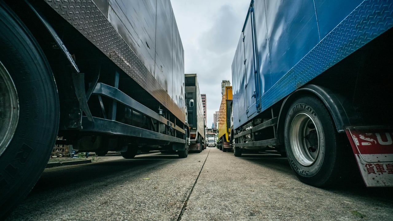 Captivating low-angle perspective of multiple trucks lined up on a street in Hong Kong.