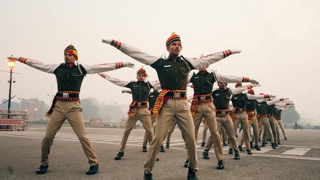 Full body ethnic soldiers in traditional uniform raising arms while exercising on testing ground in early morning