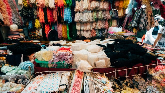 A bustling market stall showcasing a variety of vibrant fabrics and textiles, perfect for fashion and design.