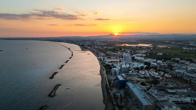 Aerial view of Limassol's coastline during sunset, showcasing the vibrant city and serene sea.