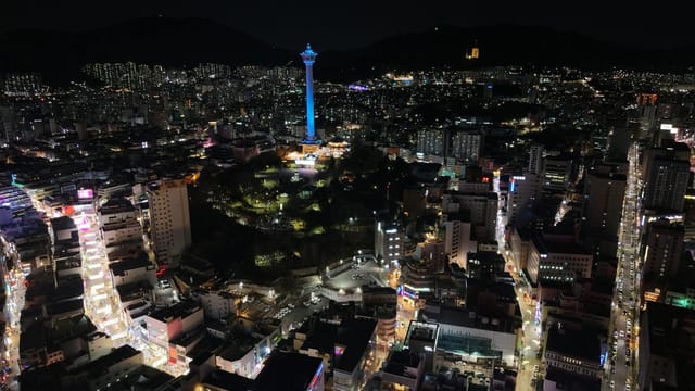 Stunning night aerial view of Busan, South Korea, highlighting the iconic tower and city lights.
