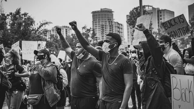 A powerful image of protesters raising fists during a Black Lives Matter rally in an urban setting.