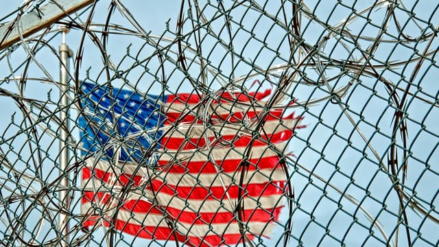USA flag seen through barbed wire, symbolizing freedom and protection