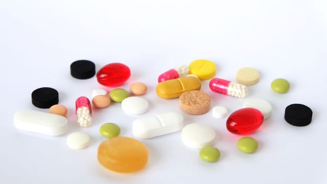 Various colorful pills and tablets scattered on a white surface, representing medication.