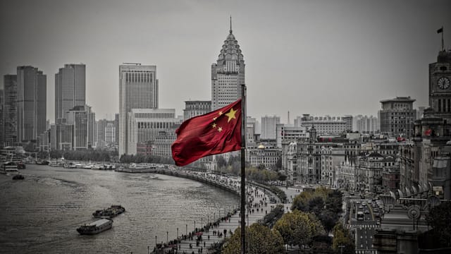 A striking view of the Chinese flag flying over the iconic skyline of Shanghai, showcasing the urban cityscape.