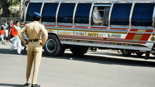 Vibrant painted bus and traffic controller on a busy street in Pakistan.