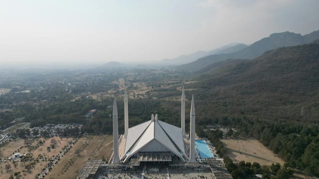 Bird's-eye view of the iconic Faisal Mosque with distant landscape in Islamabad, Pakistan.