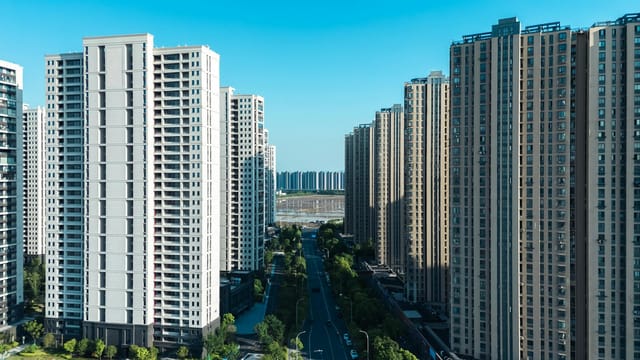 Aerial view of residential skyscrapers in Hangzhou, China, under a clear blue sky.