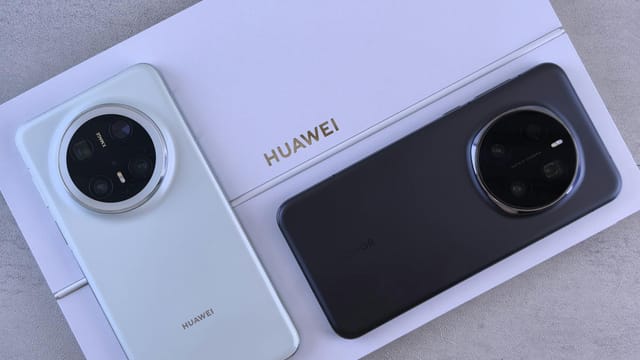 Two smartphones on a Huawei-branded packaging, one white and one black, showcasing modern design.