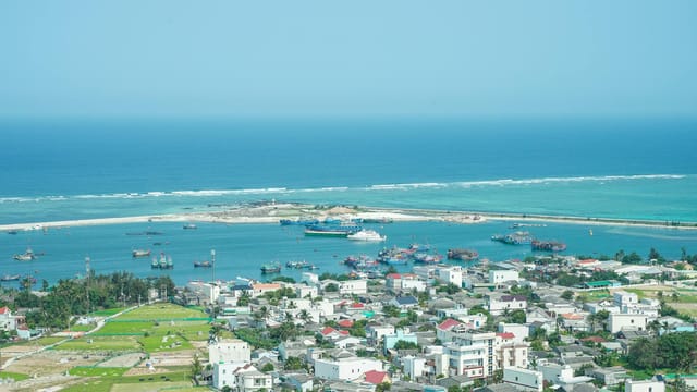 Aerial view of Ly Son Island harbor with boats and vibrant buildings, showcasing the tranquil turquoise sea.