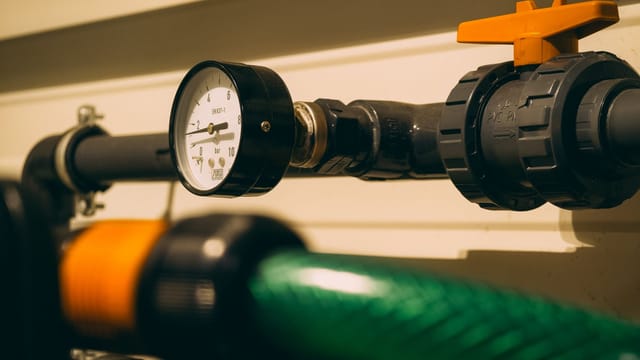Close-up view of an industrial pressure gauge attached to piping. Ideal for engineering or industry visuals.