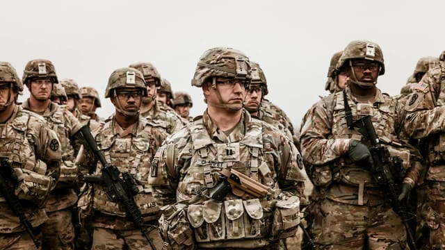A diverse group of soldiers in camouflage uniforms standing with rifles.