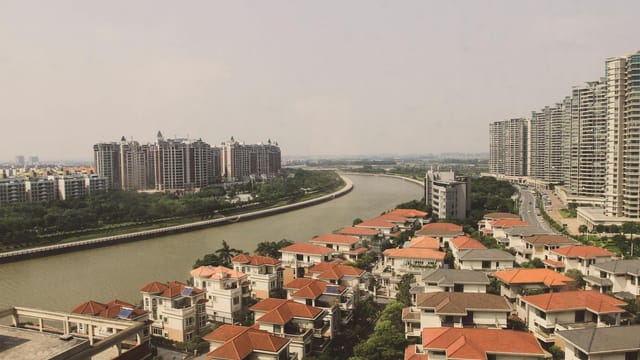 Aerial view of cityscape, showcasing modern buildings and a winding river on a sunny day.