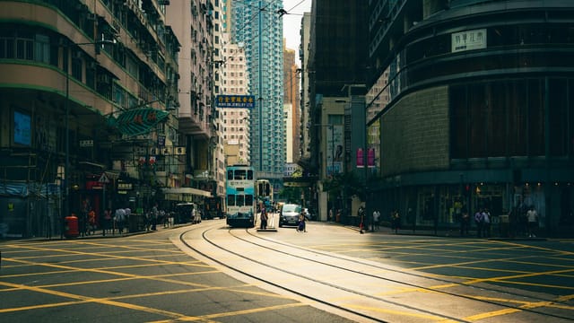Vibrant city street with trams, vehicles, and urban architecture under daylight.