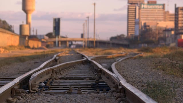 Captured railway tracks leading to Lusaka's cityscape at dusk.